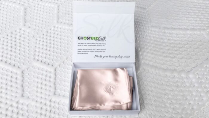 Blush pink GhostBed silk pillowcase in minimalistic packaging for luxurious sleep experience.