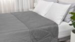 Neatly made bed with gray quilted blanket and white pillows in serene bedroom setting.