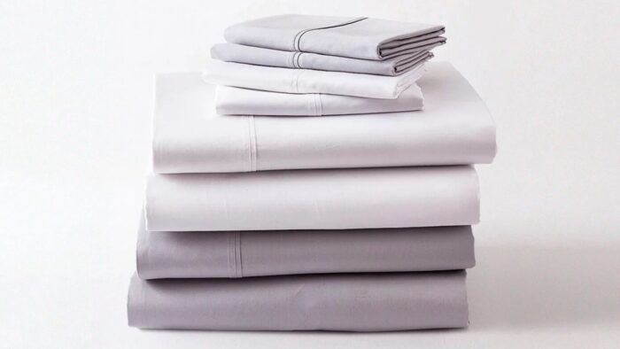 Luxurious gray and white bed linens, neatly stacked, showcasing quality and sophisticated simplicity.