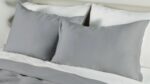 Minimalist gray and white bedding with plush pillows and soft natural light.