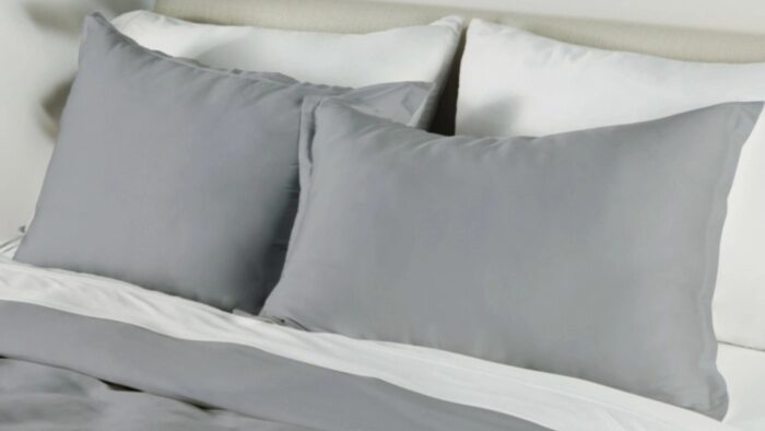 Minimalist gray and white bedding with plush pillows and soft natural light.