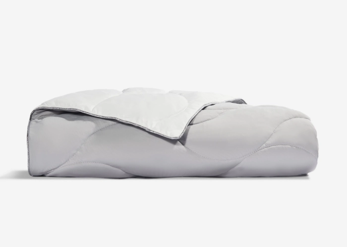 Soft light gray quilted comforter with elegant trim, ideal for modern bedroom decor.