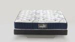 White tufted mattress with navy border against neutral background for stylish, modern comfort.