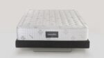 Luxurious white Magniflex mattress on elegant dark base with tufted, quilted surface.