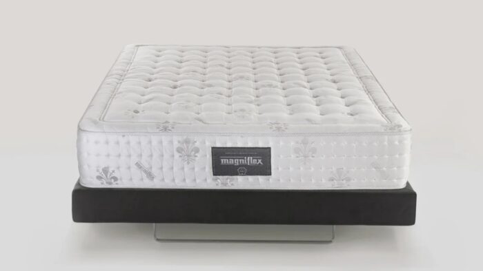 Luxurious white Magniflex mattress on elegant dark base with tufted, quilted surface.