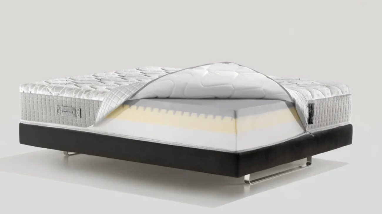 Modern white mattress on a sleek black frame with exposed foam layers for comfort.