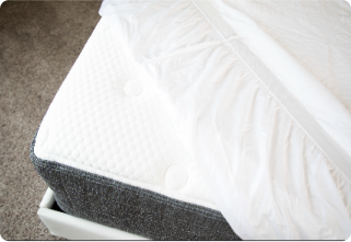 Close-up of quilted mattress on contemporary bed frame with soft carpet flooring.