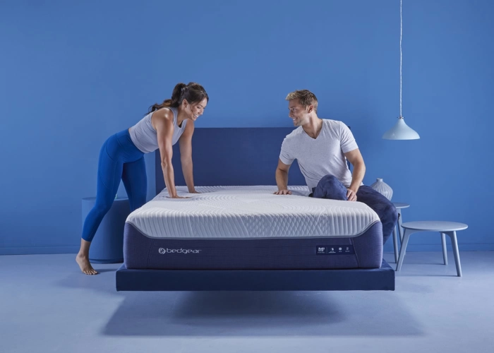 Modern blue bedroom with playful couple on stylish bed, promoting comfort and relaxation.