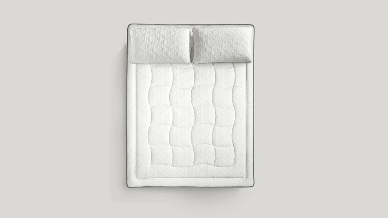 Luxurious white quilted mattress and pillows for elegant, minimalistic bedroom comfort.