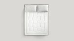 Luxurious white quilted mattress and pillows for elegant, minimalistic bedroom comfort.