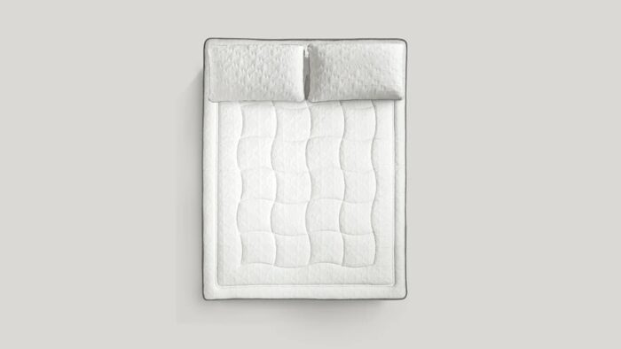 Luxurious white quilted mattress and pillows for elegant, minimalistic bedroom comfort.