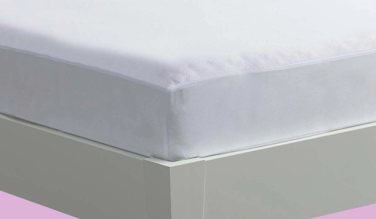 White fitted sheet over mattress with pink background creating a serene, restful bedroom ambiance.
