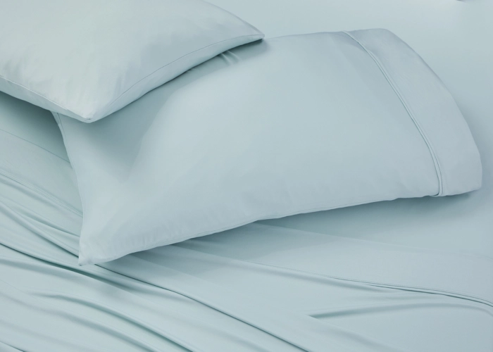 Minimalist pale blue bed with soothing bedding and pillows for a tranquil bedroom ambiance.