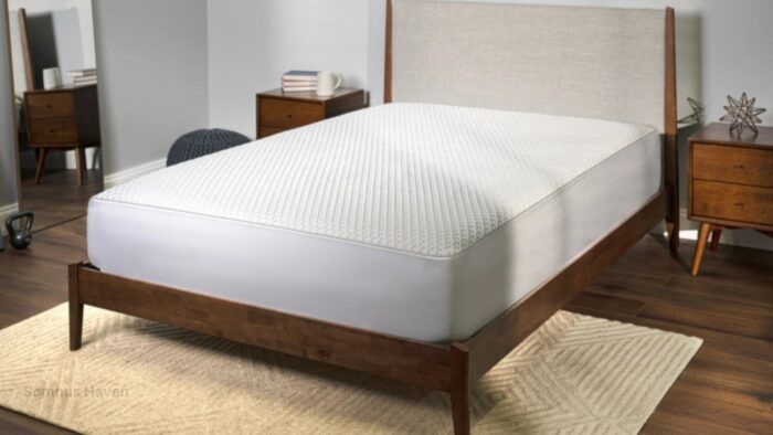 Modern bedroom with sleek bed, light upholstered headboard, and white textured mattress protector.