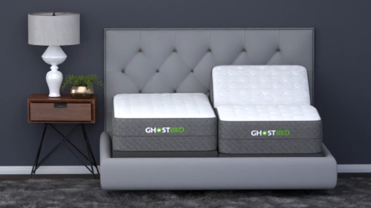 Modern bedroom with light gray bed, GhostBed mattresses, and walnut nightstand. Cozy ambiance.