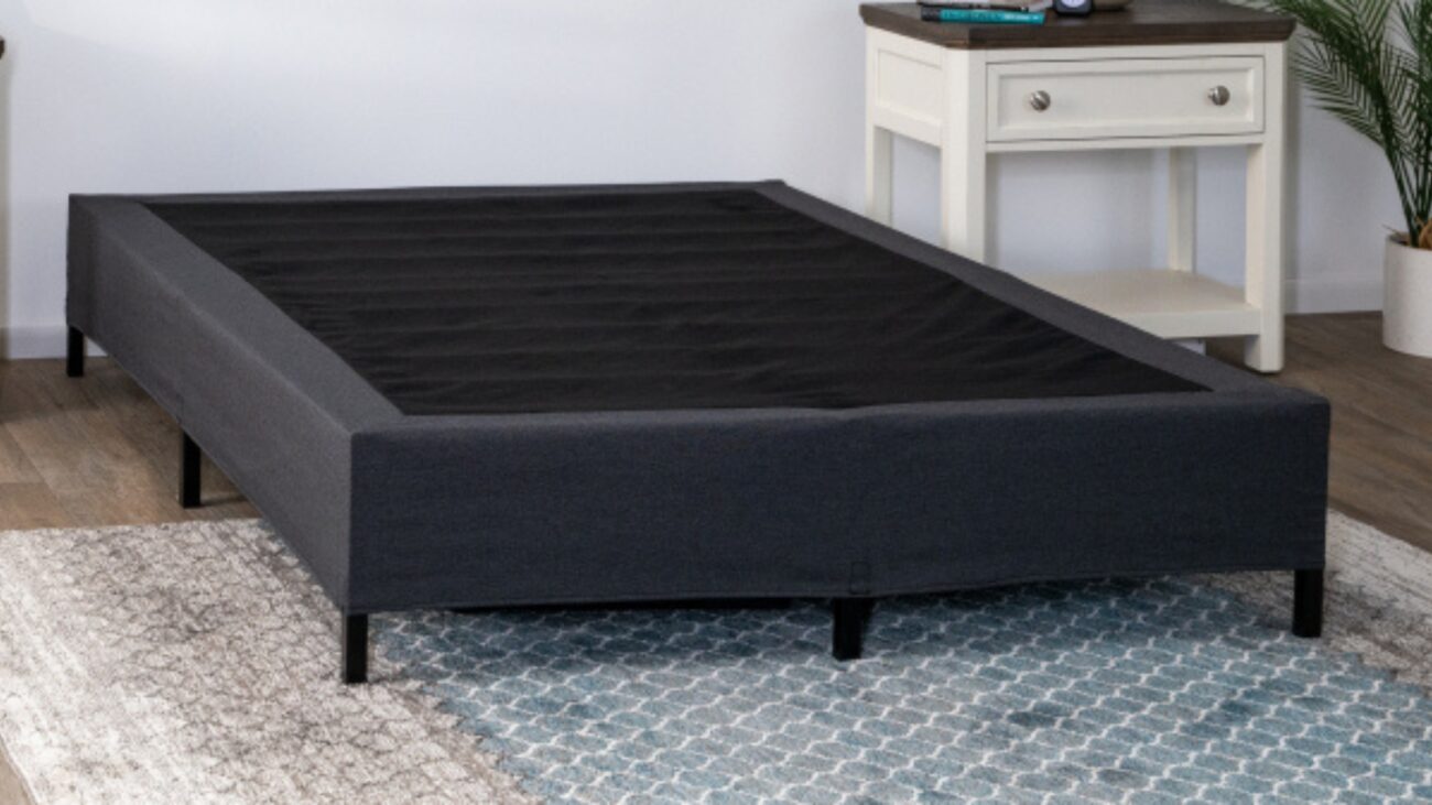 Modern minimalist dark gray bed frame with slatted base on geometric rug.