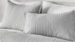 Modern gray and white bedding set with textured pillows for a stylish, serene bedroom.