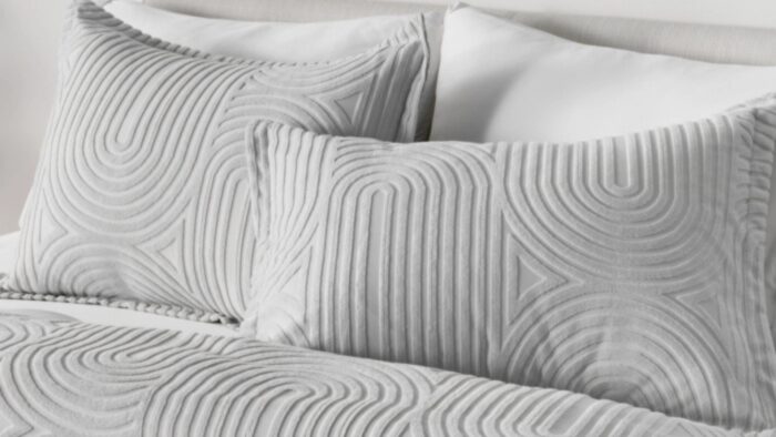 Modern gray and white bedding set with textured pillows for a stylish, serene bedroom.