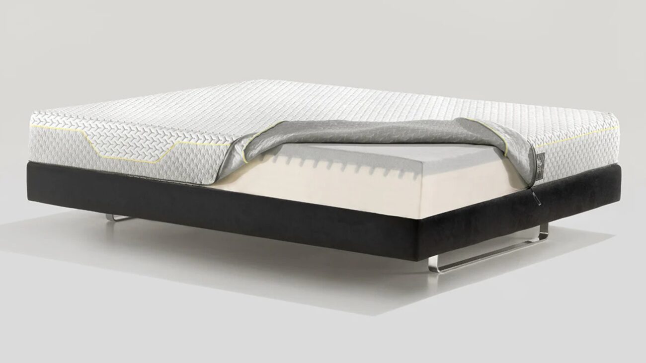 Modern minimalist bed with quilted mattress, grey blanket, and dark base for stylish comfort.
