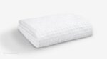 Textured white ergonomic pillow for comfort and support in a minimalist setting.