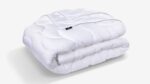 Cozy white quilted blanket with zipper, perfect for warmth and versatile home décor.