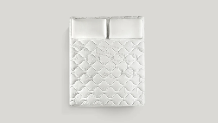 Luxurious white quilted mattress with pillows, perfect for modern and tranquil bedroom decor.