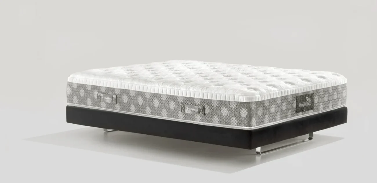 Modern plush mattress with geometric patterns on a sleek black platform in minimalist setting.