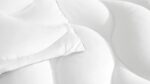 Minimalist white quilted comforter and pillow set for a cozy bedroom atmosphere.