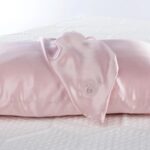 Luxurious satin pink pillow with elegant draped fabric, highlighting sophistication and comfort.
