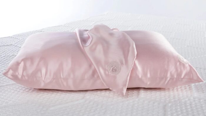 Luxurious satin pink pillow with elegant draped fabric, highlighting sophistication and comfort.
