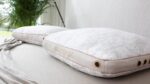 Cozy plush pillows with greenery on a minimalist bed in soft lighting ambiance.