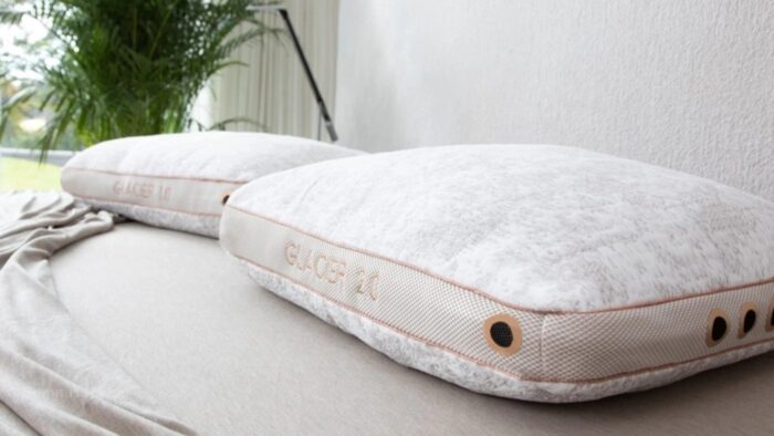 Cozy plush pillows with greenery on a minimalist bed in soft lighting ambiance.