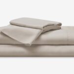 Neatly stacked taupe bedding sheets evoke comfort and tranquility for restful sleep.