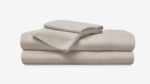 Neatly stacked taupe bedding sheets evoke comfort and tranquility for restful sleep.
