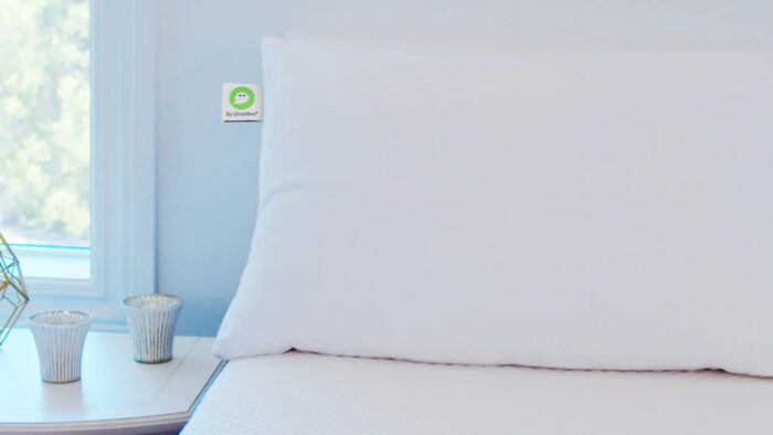 Minimalist bedroom with white pillow, ribbed vases, and soft blue walls.