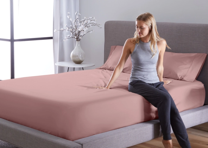 Modern bedroom with muted pink bedding, serene atmosphere, and natural light.
