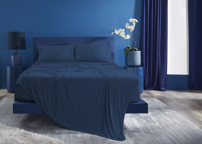 Elegant blue bedroom with modern decor, soft lighting, and a potted orchid for tranquility.