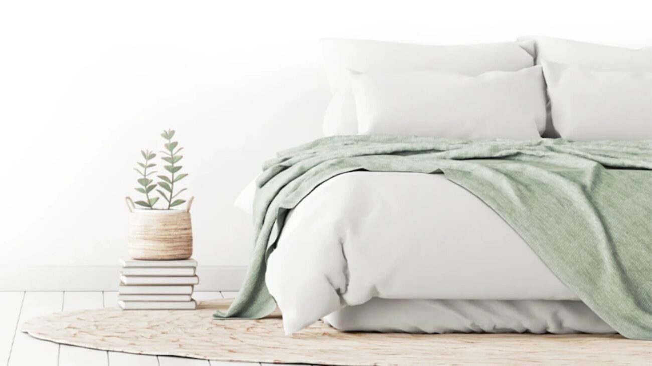 Minimalist bedroom with a white bed, green throw, and natural textures for serene ambiance.
