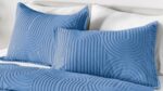 Soft blue quilted pillows add elegance to crisp white bedding.