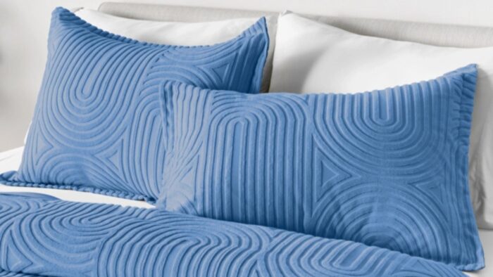 Soft blue quilted pillows add elegance to crisp white bedding.