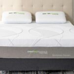 Modern bedroom with Somnus Haven mattress, tufted headboard, minimalist nightstands, and patterned rug.