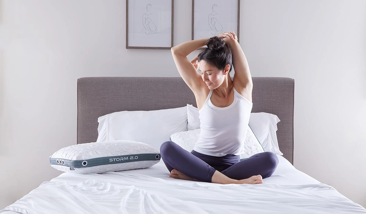 Woman meditating in a serene bedroom with innovative Storm 2.0 pillow.