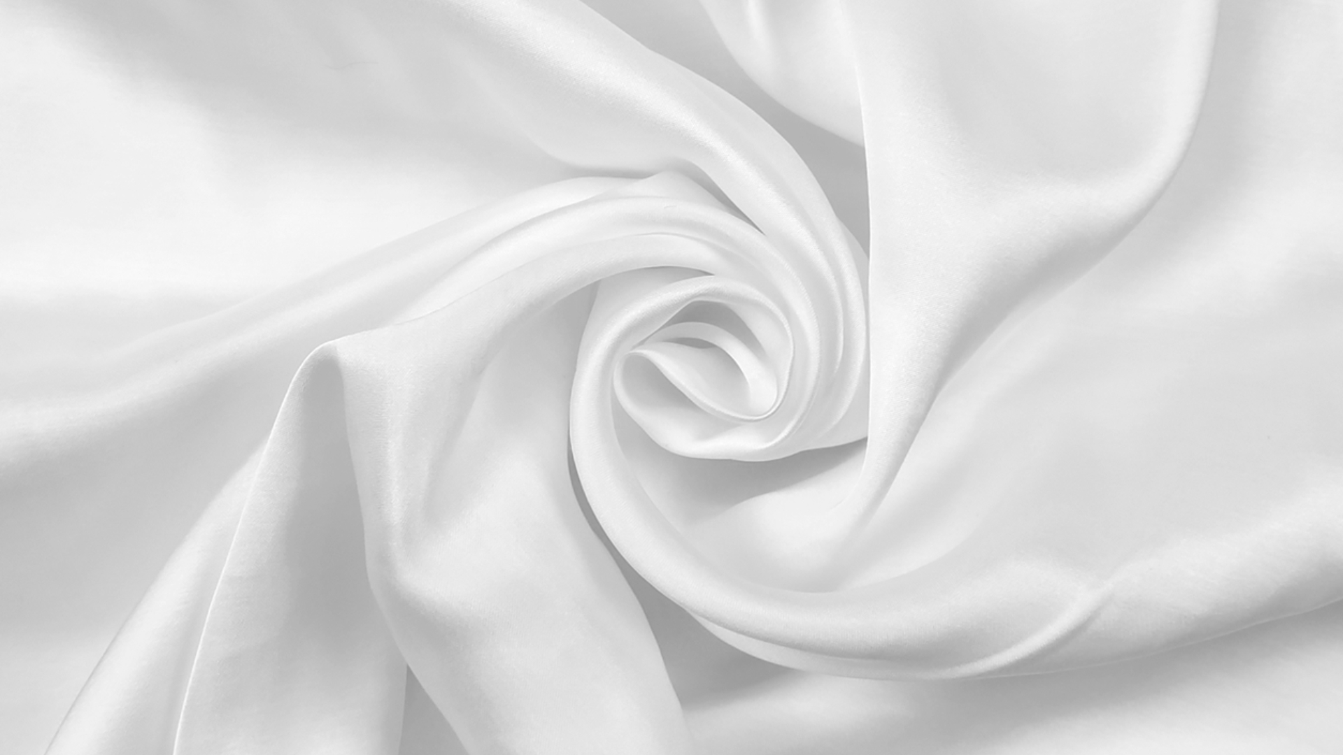Close-up of luxurious white satin fabric, showcasing elegant spiral folds and glossy texture.
