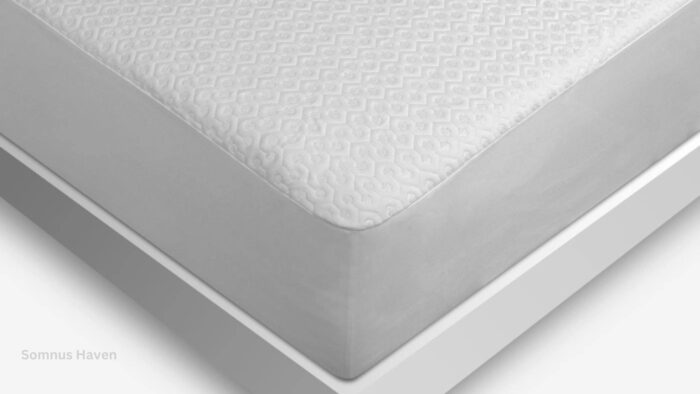 White mattress with geometric textured sheet on modern light bed frame.