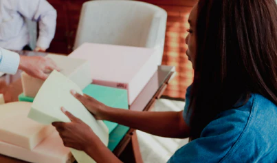 Woman examining foam sheets in collaborative design studio for creative product development.