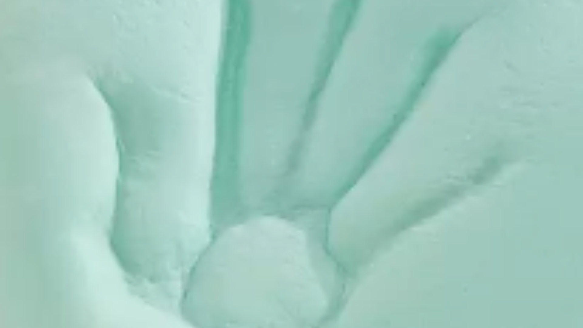 Mint green foam with a detailed handprint impression suggesting tranquility and connection.