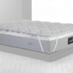 Plush gray quilted mattress in minimalist setting, emphasizing elegance and comfort.